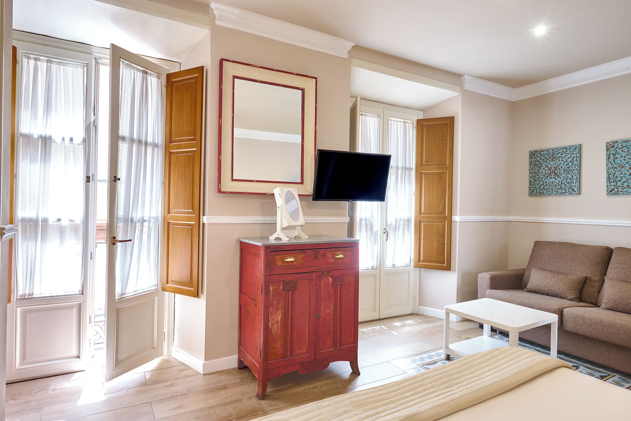 Een kamer met een houten kast, een televisie, een bank en een raam met gordijnen.
