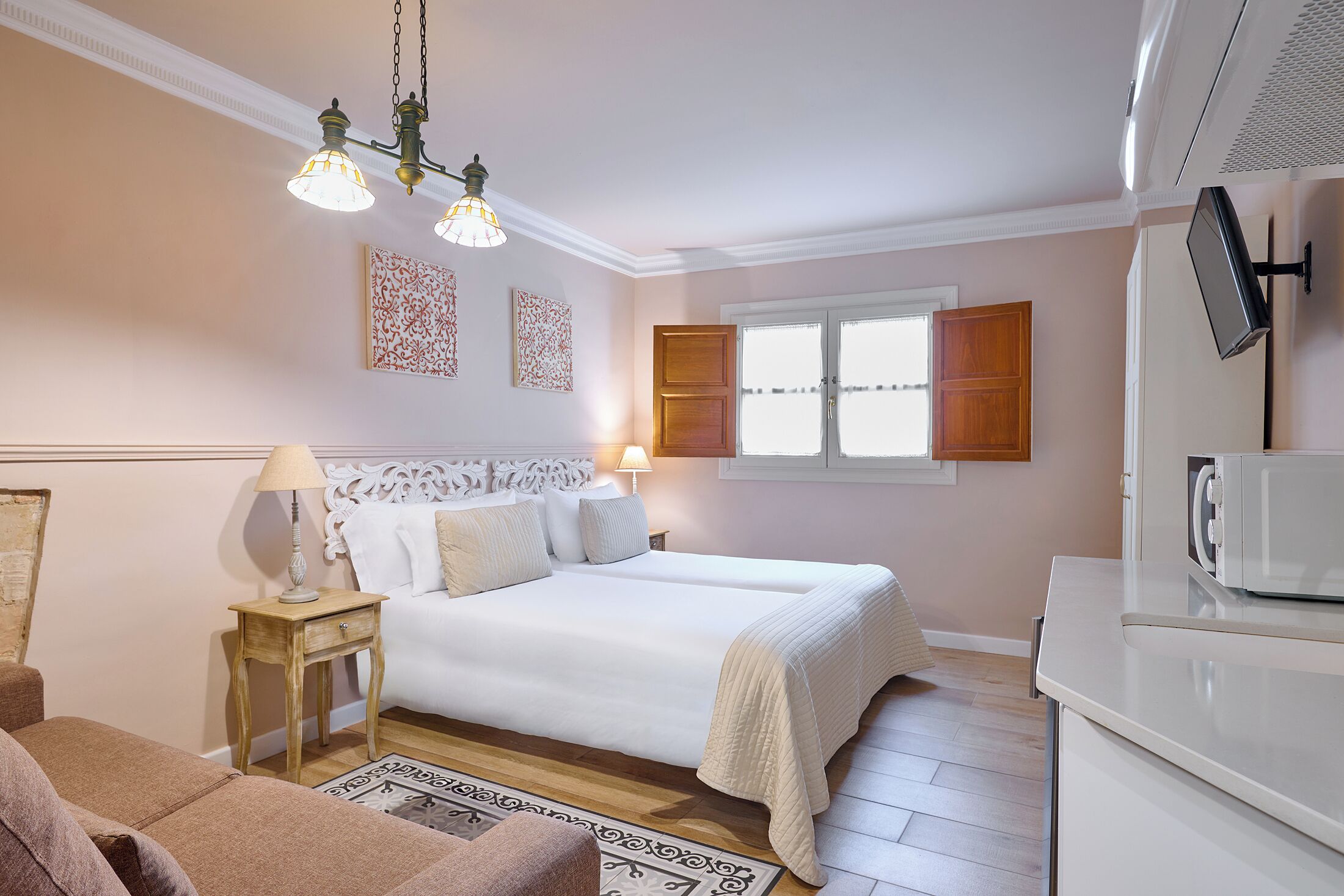 A bedroom with a bed, bedside table, lamp, and a television.