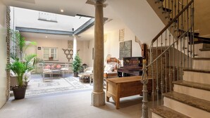 A spacious living area with a piano, a staircase, and a view of the outside. - Apartamentos Luna Suites Palacio Almagra (Granada)