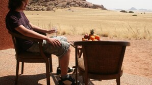 Una persona sentada en una mesa con un frutero encima, al aire libre frente a un paisaje rocoso.