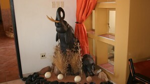 Una habitación con una escultura decorativa de un oso y un alce, un pequeño aparador y una cortina roja.