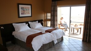 Una habitación de hotel con una cama grande, una mesita y un balcón con vistas.
