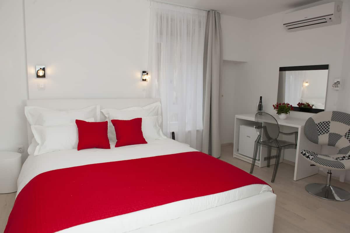 Una habitación de hotel con una cama grande, un escritorio, una silla y un espejo.