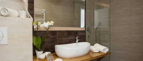 A modern bathroom with a large white sink, a glass shower enclosure, and a wooden vanity.