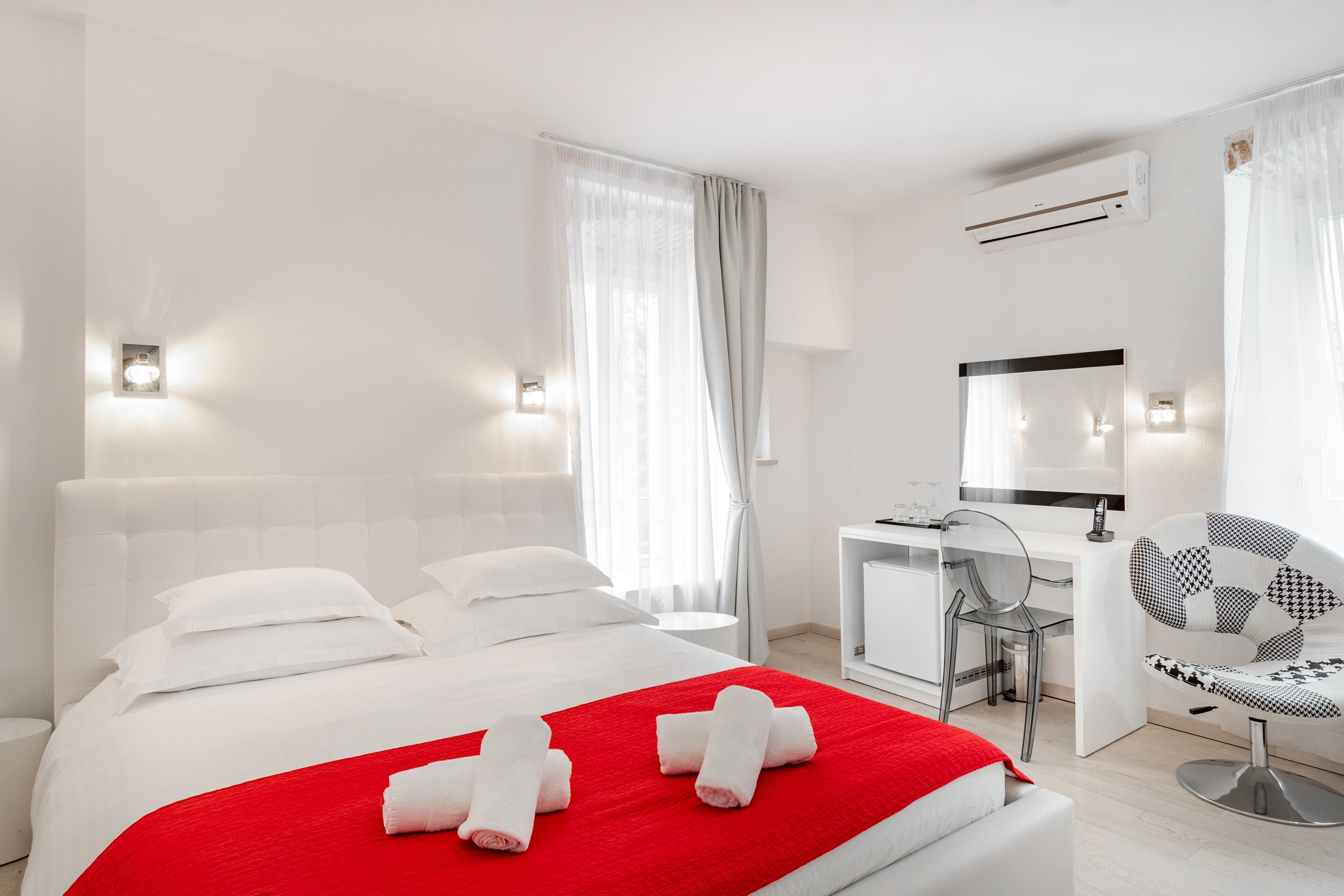Een moderne hotelkamer met een groot bed, een bureau, een stoel en een airconditioning.