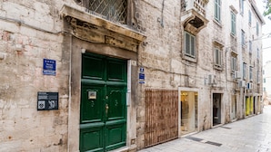 A historic building with a green double door, a plaque indicating a heritage site, and a storefront with a sign. - Palace Tartaglia (Split)