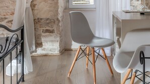 A room with a stone wall, a window with a view of a building, a desk, and two chairs. - Palace Tartaglia (Split)