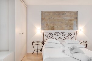 Een slaapkamer met een bed, een tafeltje, een kunstwerk aan de muur en een deur.