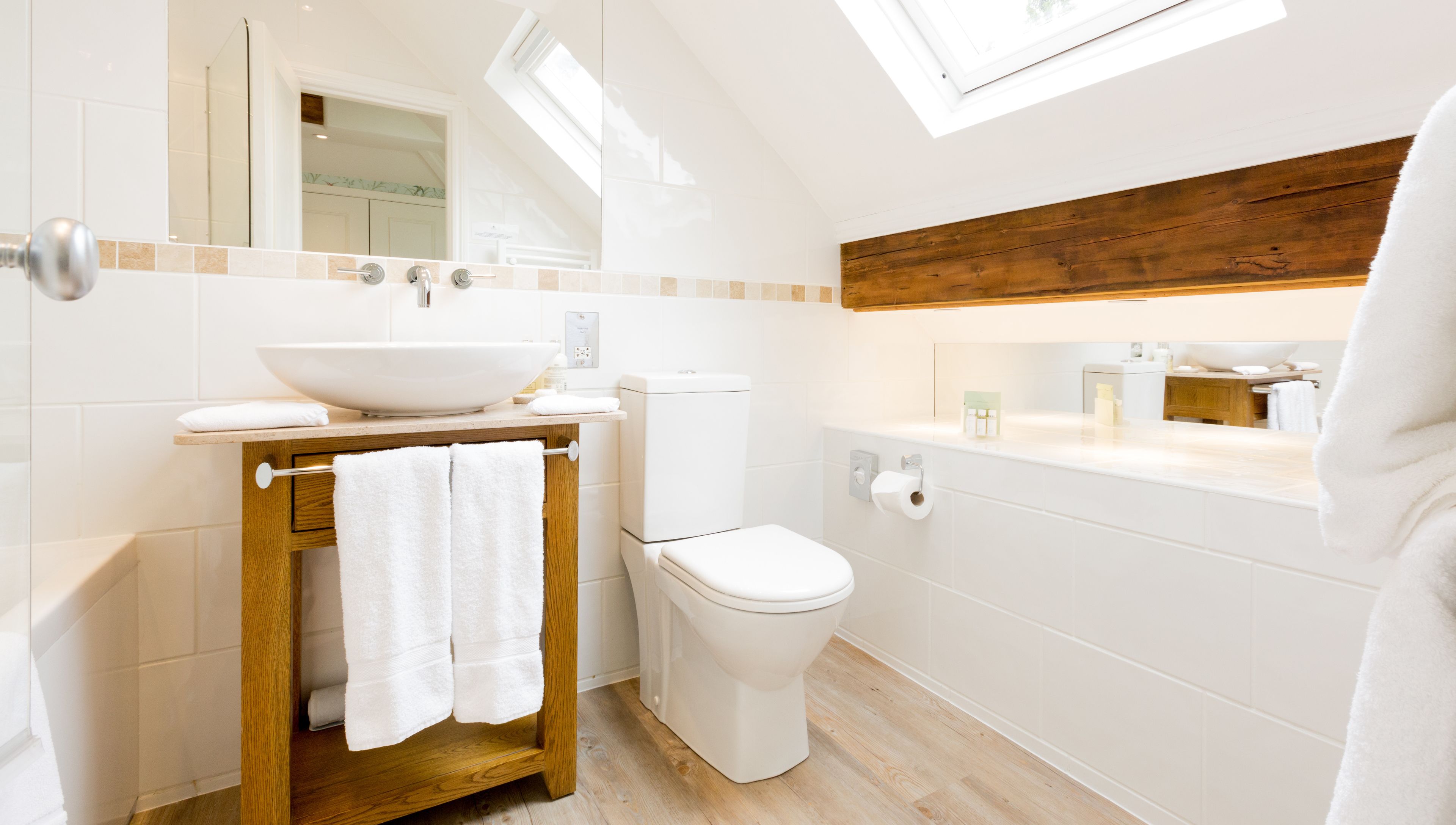 A modern bathroom with a large vessel sink, toilet, and a wooden vanity.