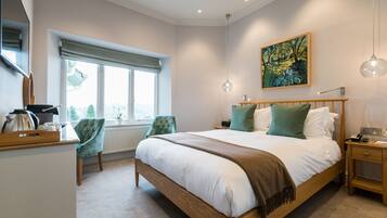 A bedroom with a large bed, a wooden nightstand, a chair, a window with a view, and a painting on the wall.