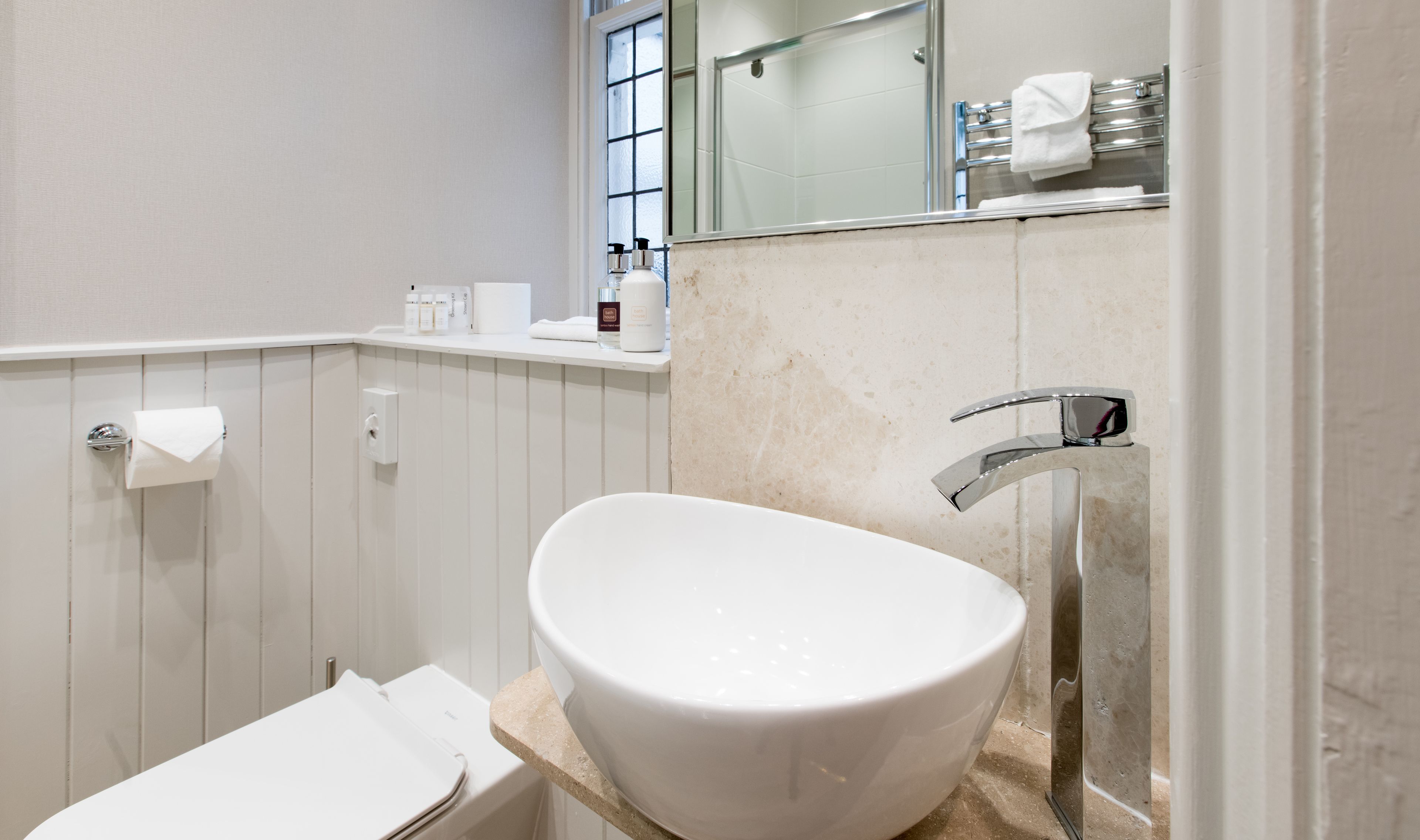 A modern bathroom with a freestanding bathtub, a toilet, and a sink with a chrome faucet.