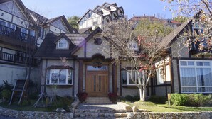 Una casa de dos plantas con fachada de piedra, puerta principal de madera y un pequeño porche.
