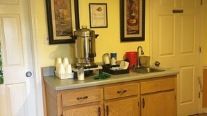 Una cocina con armarios de madera, una cafetera y un reloj en la pared.
