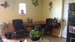 Una habitación acogedora con una mesa redonda, dos sillones de cuero, un sofá y una planta en maceta.