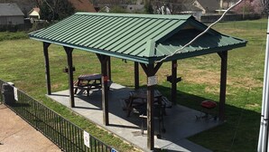 Un área de picnic techada con mesas y bancos, un área de piscina cercada y un letrero que indica que no se permite nadar.