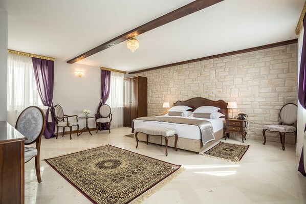 Ein Schlafzimmer mit einem großen Bett, einer Steinwand, einer Chandelüster und einem klassischen Holzstuhl.