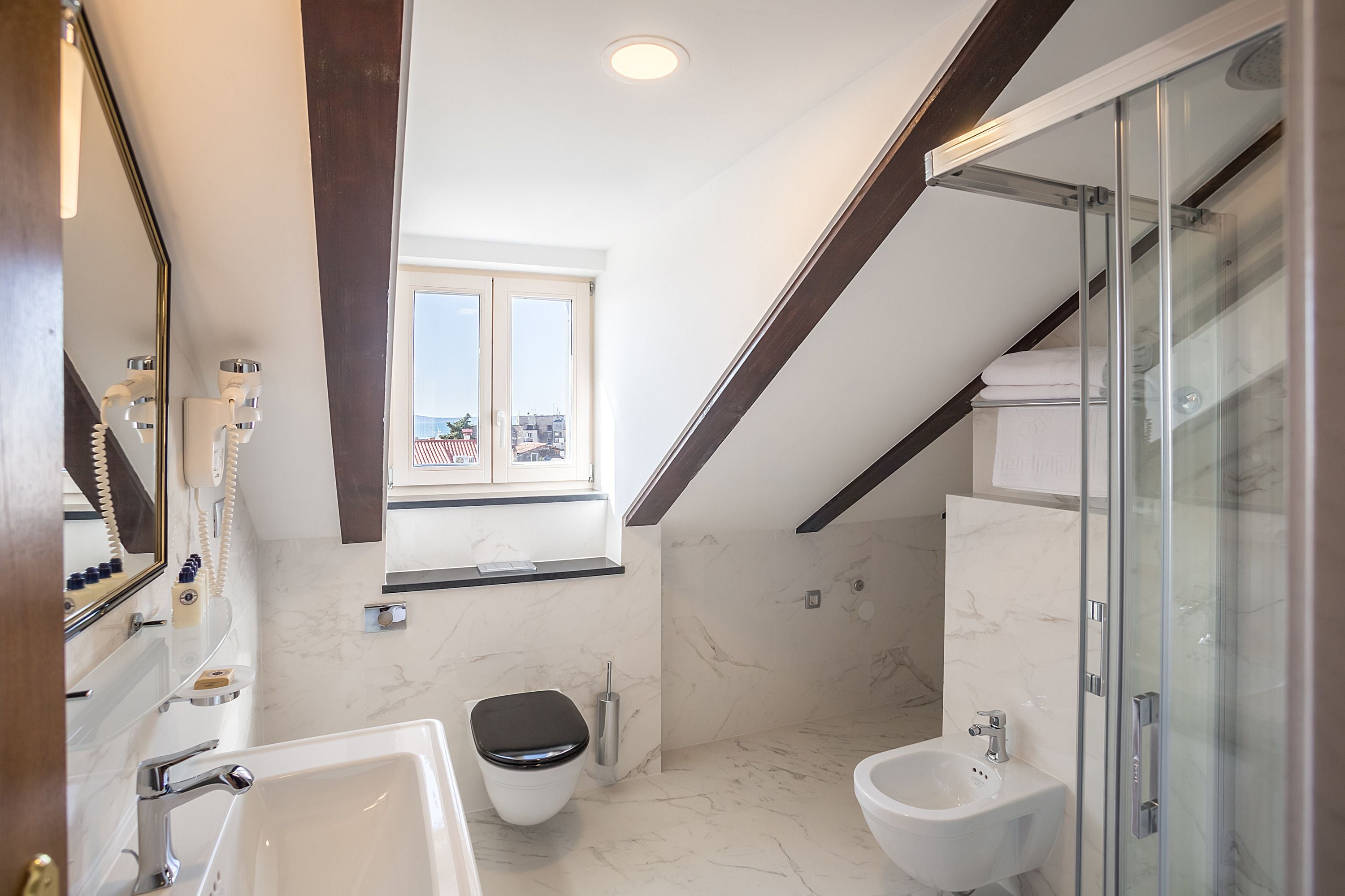 Ein modernes Badezimmer mit Toilette, Bidet und einer Duschkabine aus Glas.