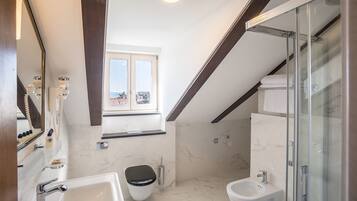 Ein modernes Badezimmer mit Toilette, Bidet und einer Duschkabine aus Glas.