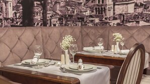 A restaurant with a tufted booth seating area and tables set for dining. - Splendida Palace (Split)
