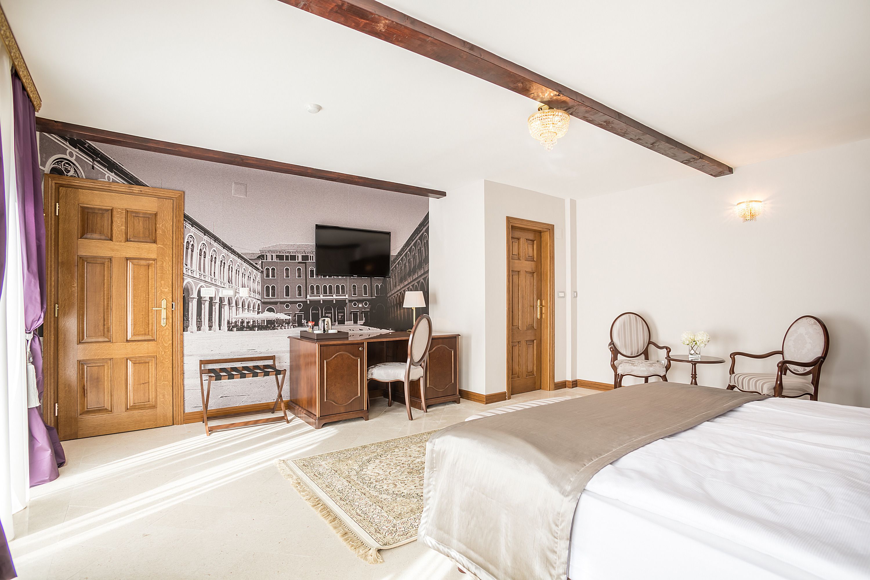 Ein Schlafzimmer mit einem Bett, einem Schreibtisch, zwei Stühlen und einem Wandbild.