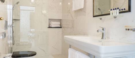 Un baño moderno con ducha de vidrio, un lavabo blanco y un espejo grande.