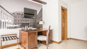 Een hotelkamer met een bureau, stoel en een groot muurschildering van een stadsstraat.