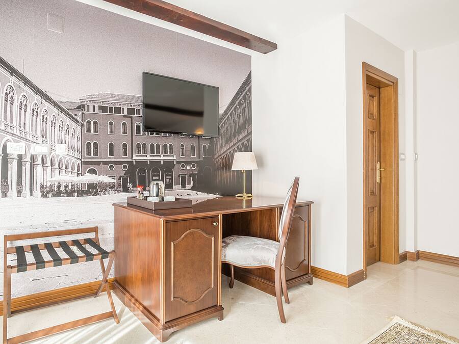 Een hotelkamer met een bureau, stoel en een groot muurschildering van een stadsstraat.