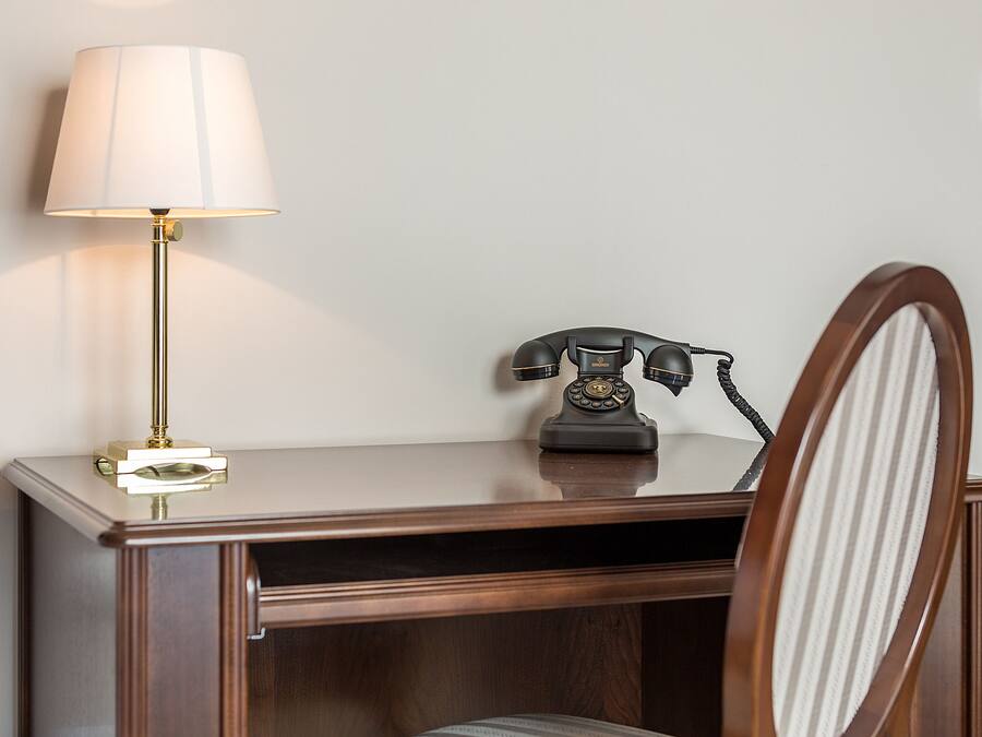 Een houten bureau met een lamp en een klassieke telefoon.