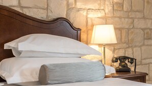 A neatly made bed with white linens and a grey pillow, a wooden headboard, a bedside lamp, and a vintage telephone on a wooden nightstand. - Splendida Palace (Split)