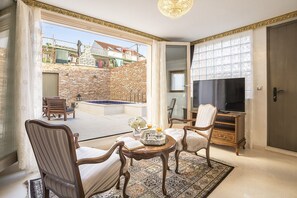 Ein geräumiger Wohnbereich mit Balkon, Fernseher und Esstisch.