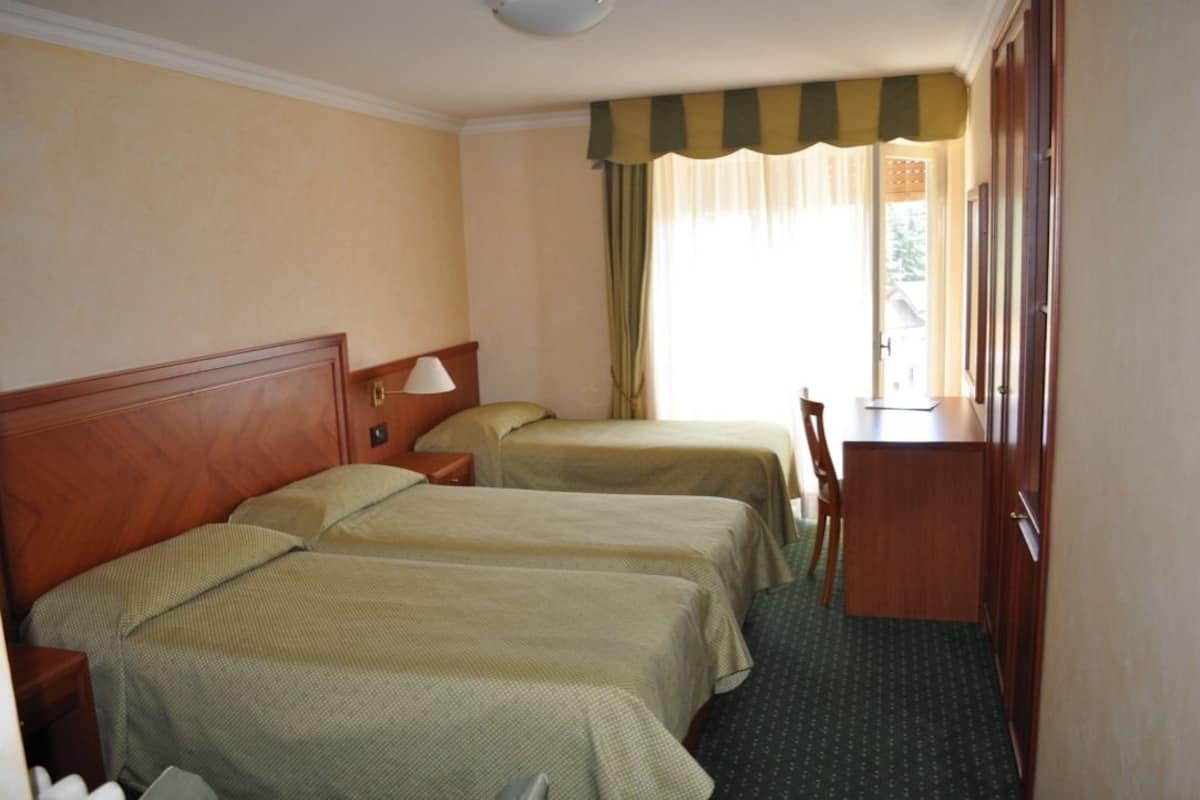 A hotel room with two beds, a desk, and a chair.