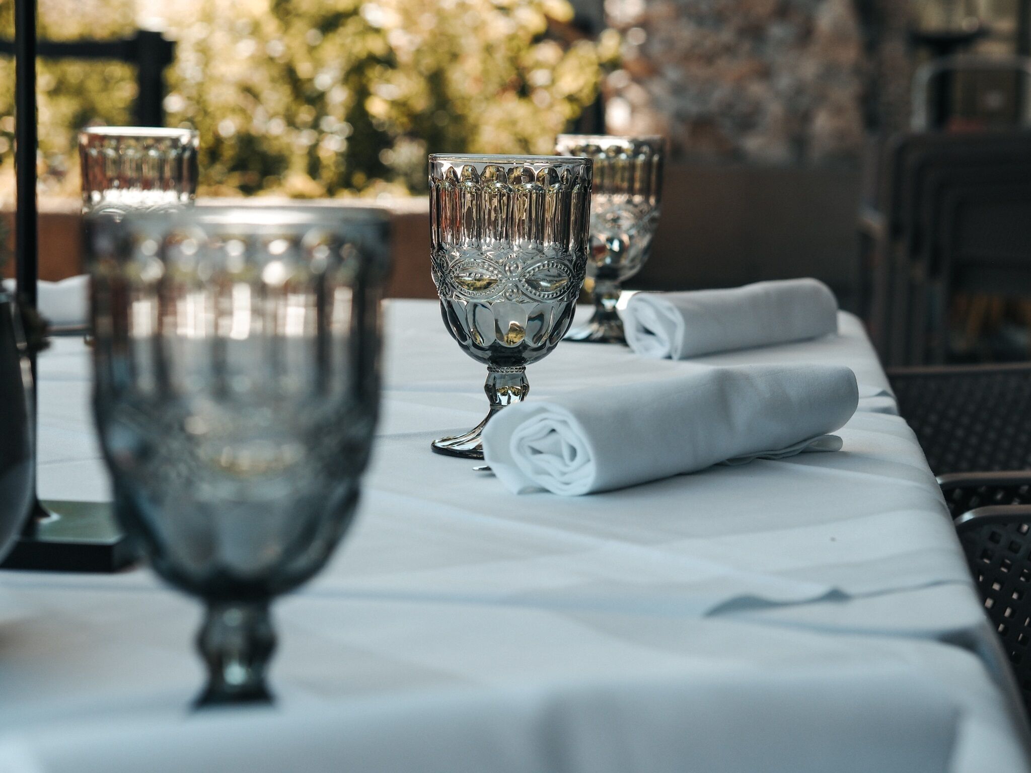 A table set with clear glass goblets and folded white napkins, suggesting a formal dining setting.
