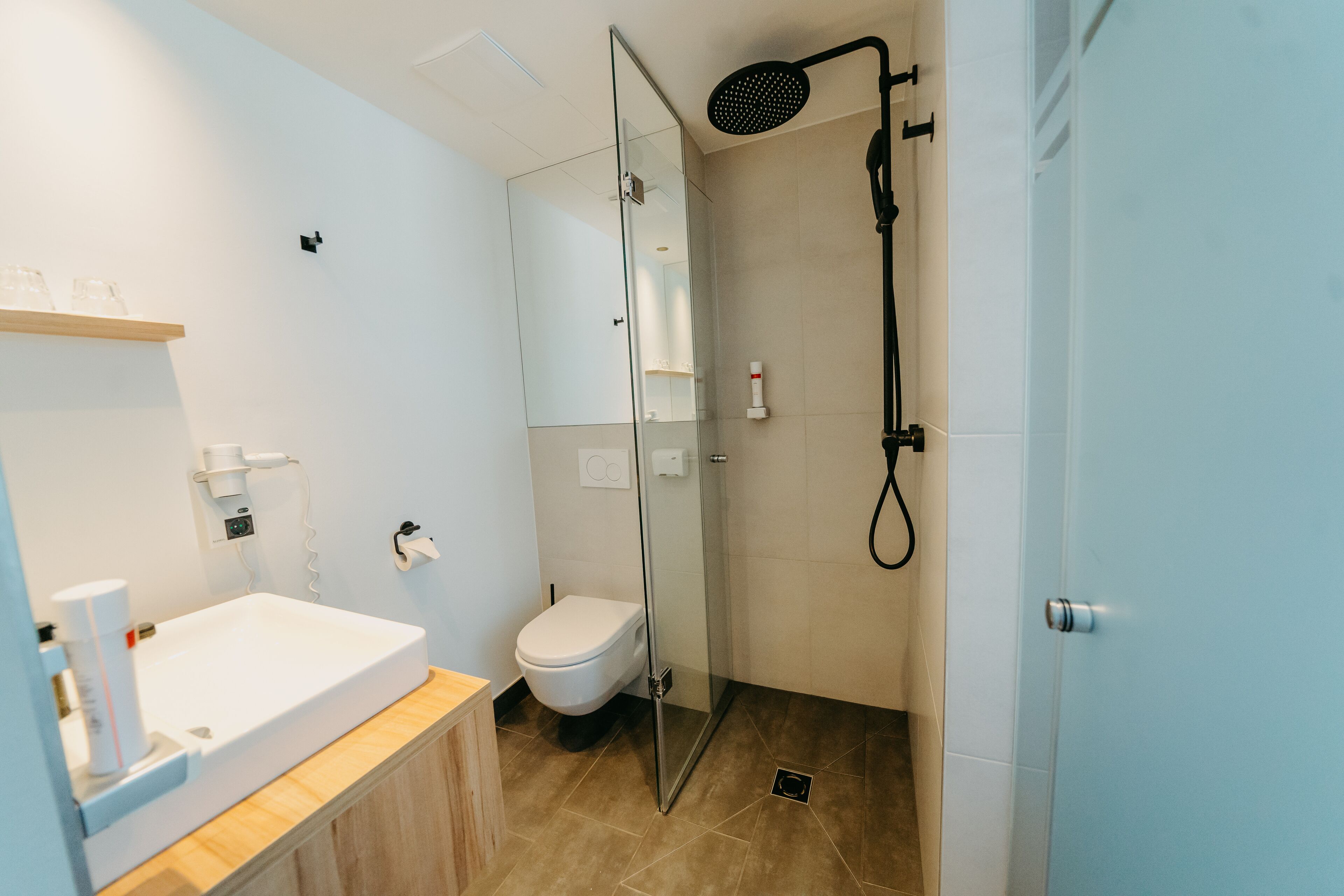 Un baño moderno con ducha de vidrio, lavamanos blanco y retrete.