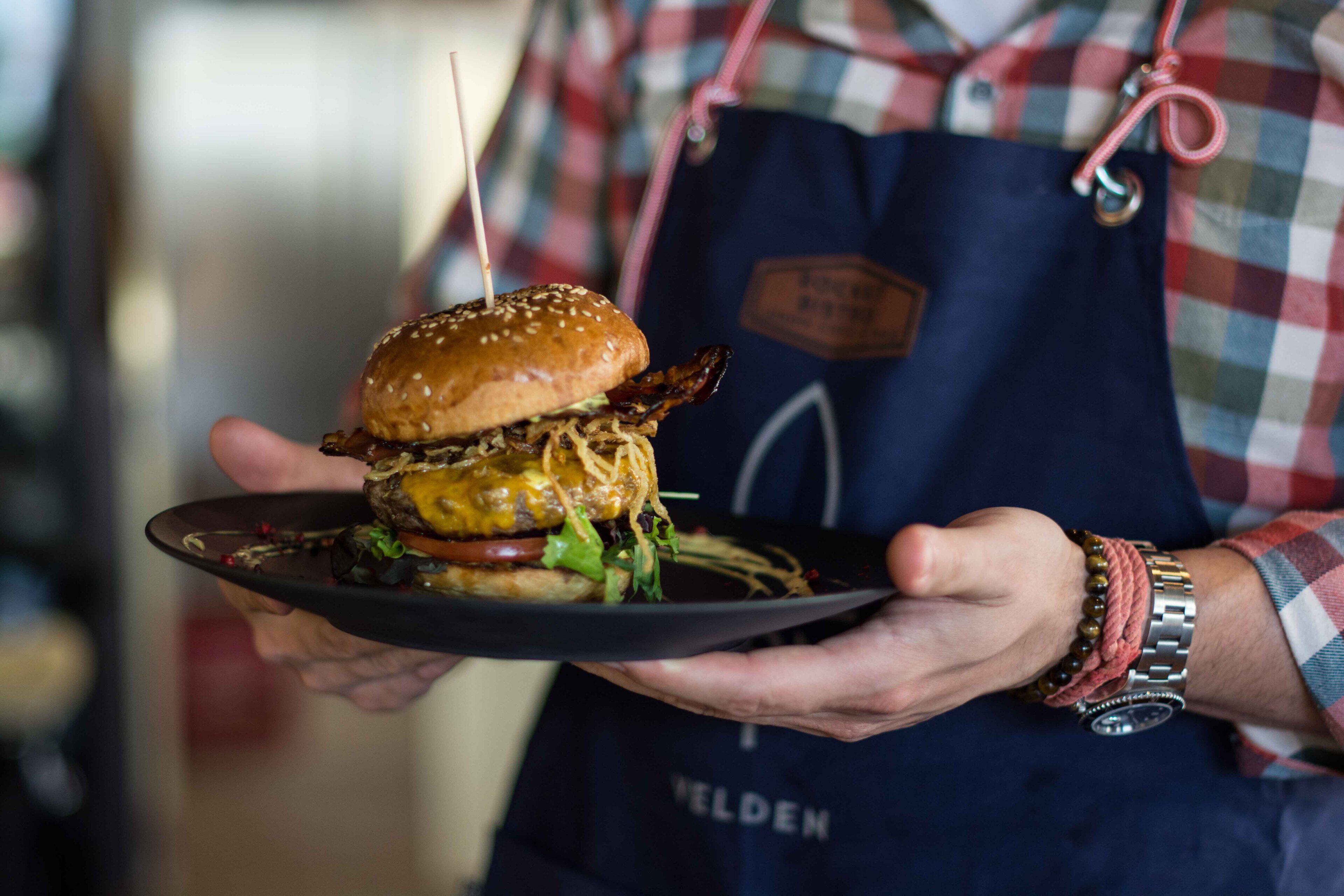 A person holding a plate with a burger.