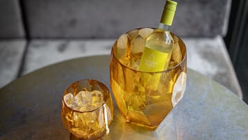 A bottle of Rocket Blanc wine and a glass with ice cubes on a round table.