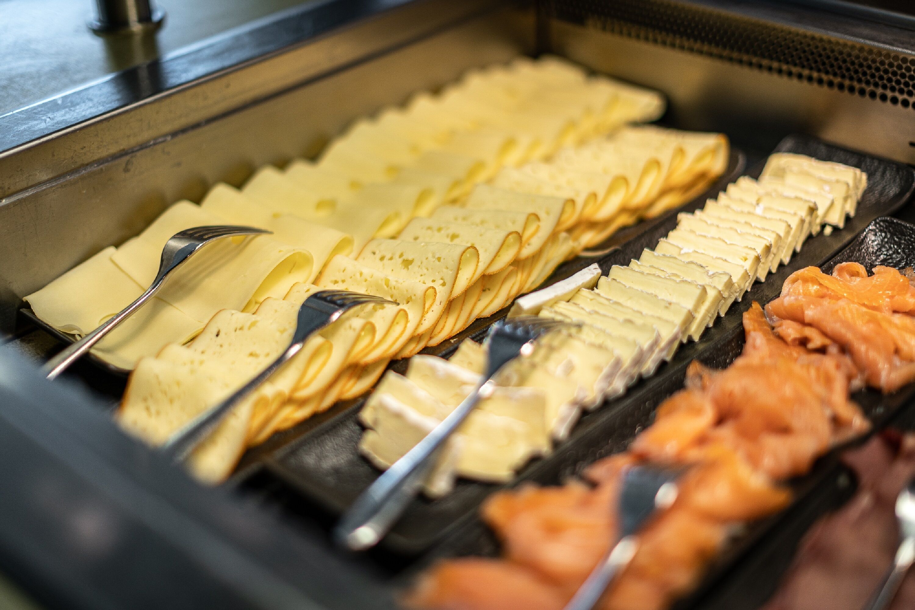 A buffet with various food items including pancakes, waffles, and salmon.