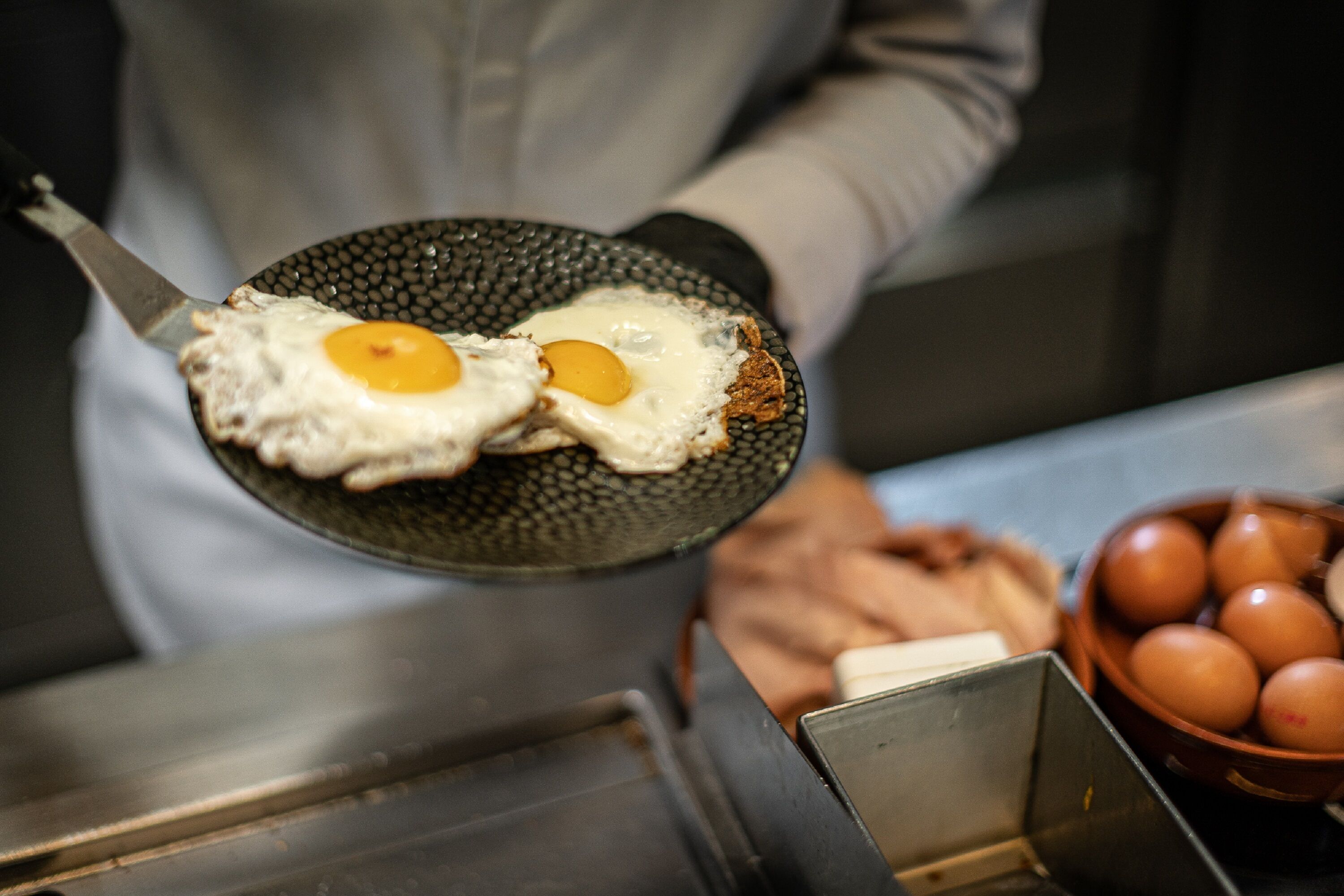 Une personne tenant une poêle à frire avec deux œufs au plat.