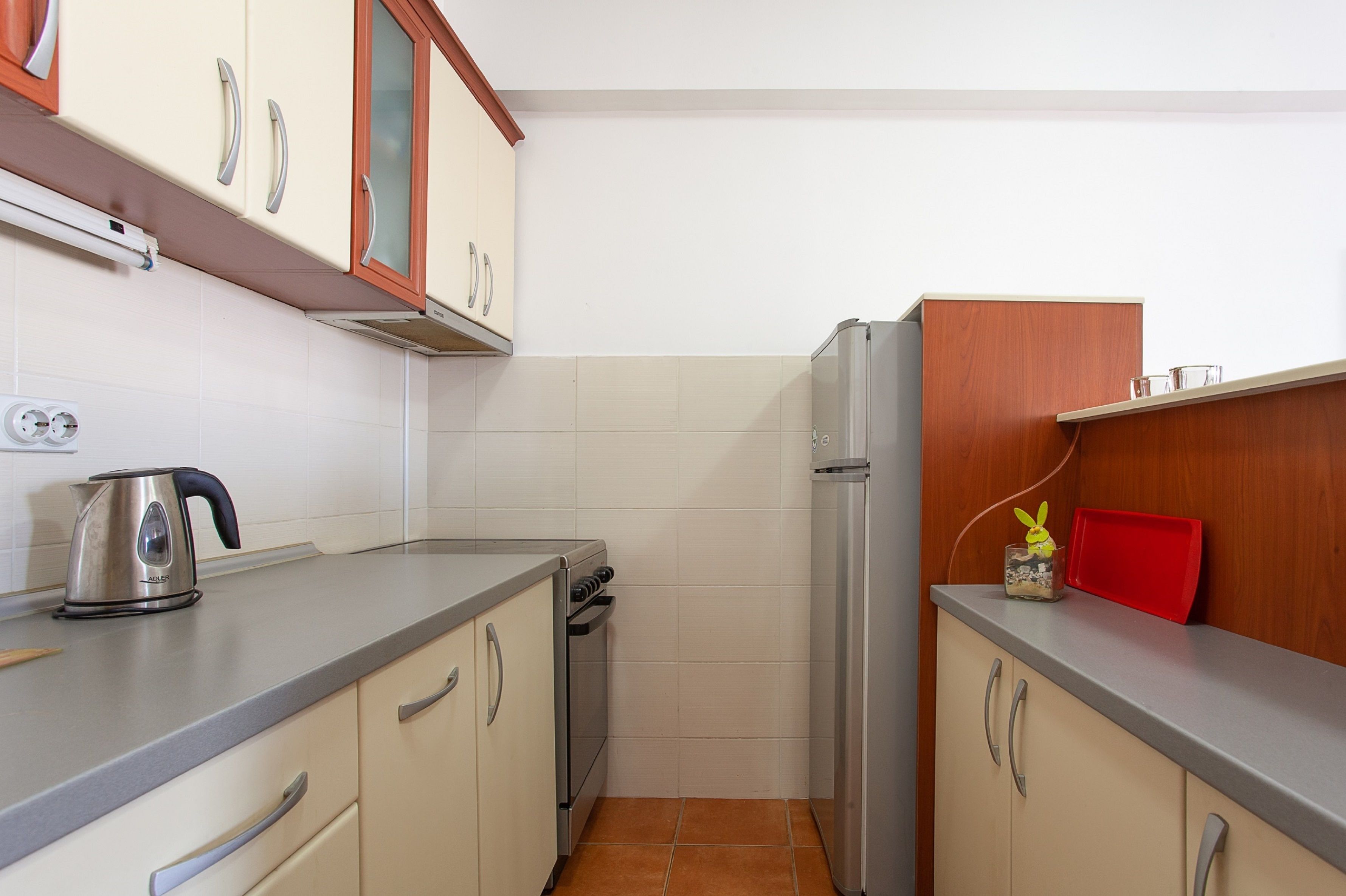 A compact kitchen with a stove, refrigerator, and cabinets.