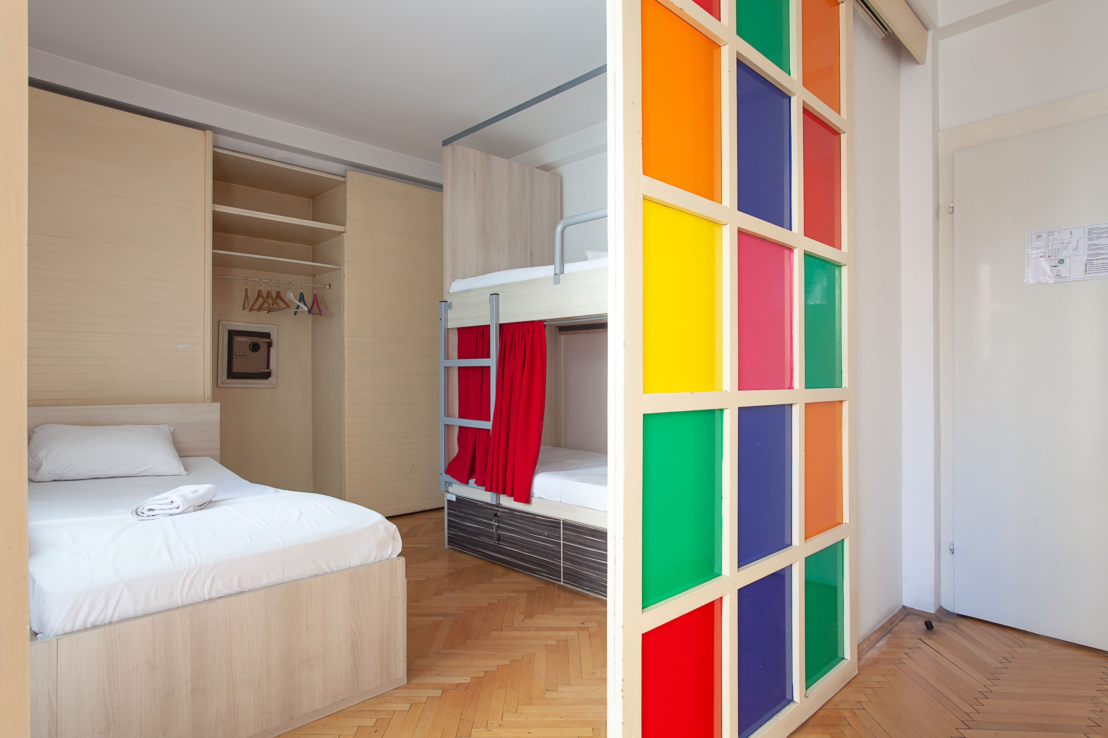 A room with a bunk bed, a wardrobe, and a door with a colorful panel.