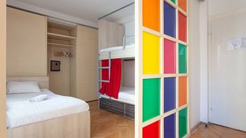 A room with a bunk bed, a wardrobe, and a door with a colorful panel.
