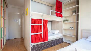 A bunk bed room with red curtains, a wooden floor, and a white bed.