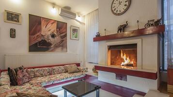 Ein Wohnzimmer mit einer Couch, einem Kamin, einer Uhr und Kunstwerken an der Wand.