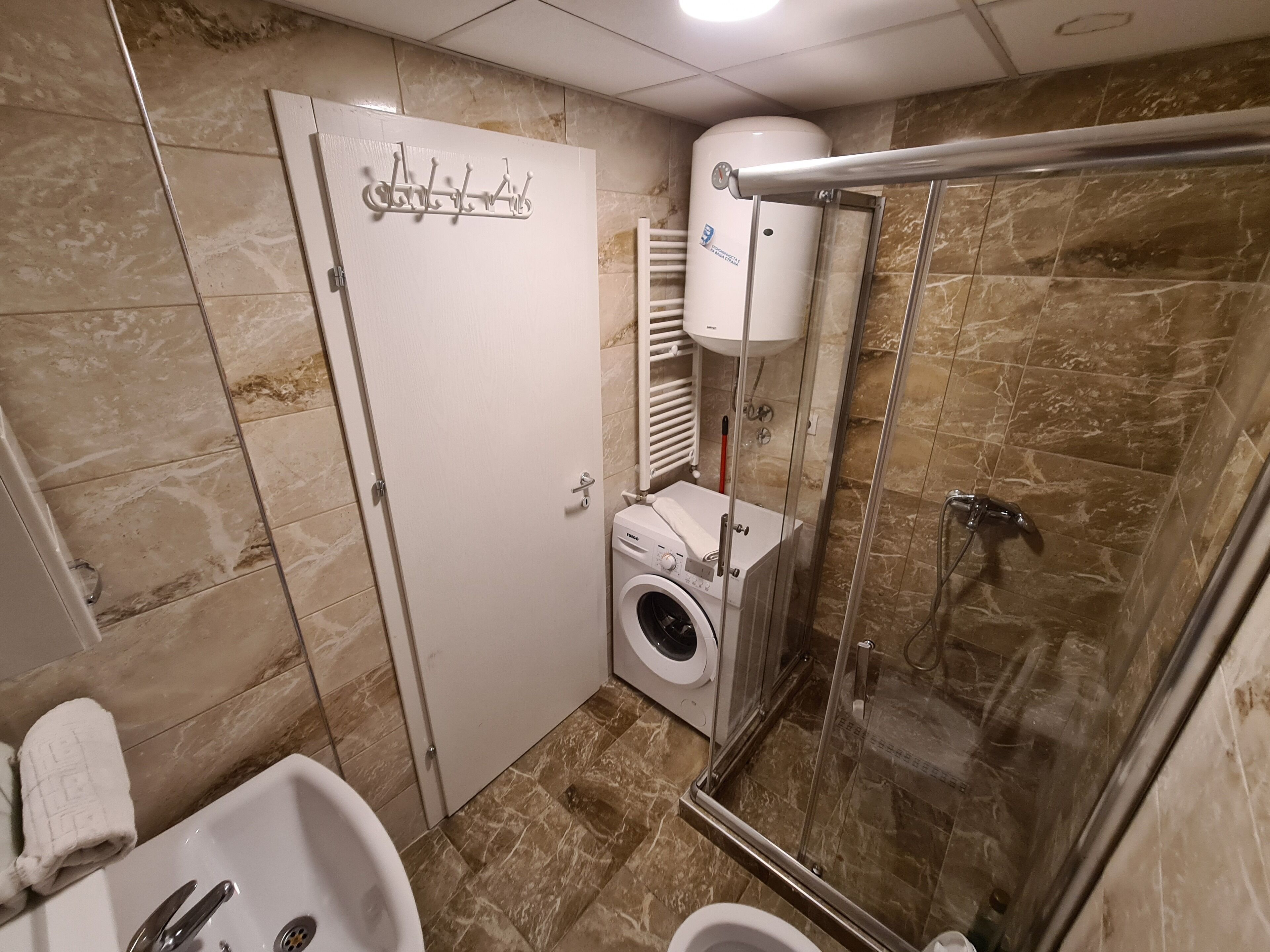Un baño pequeño con ducha, inodoro y lavadora.