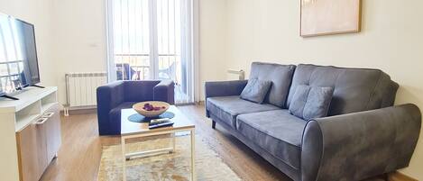 Una sala de estar moderna con un sofá gris, una mesa de centro, un televisor y un radiador.
