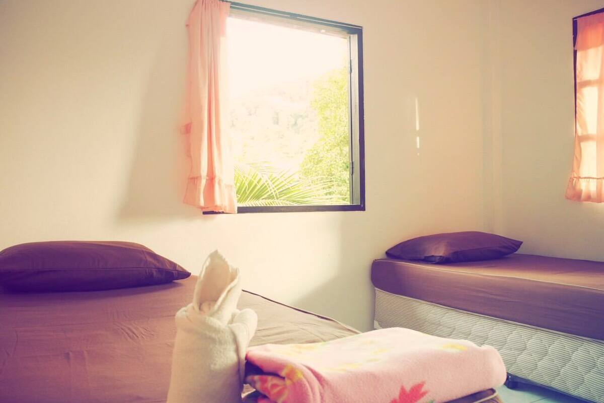Ein Zimmer mit zwei Betten, eines mit einer rosa Decke und das andere mit einem braunen Kissen.
