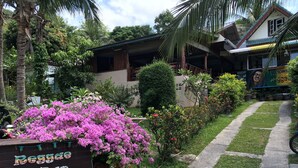 A sign for Regade Bar & Restaurant surrounded by lush greenery and a pathway. - Reggae Village (Ko Pha-ngan)
