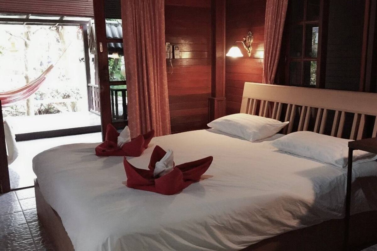 Ein Zimmer mit einem großen Bett, einem Holzkopfteil und einem Fenster mit Vorhängen.