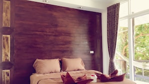 A bedroom with a large bed, dark wooden headboard, and a view of greenery through a window. - Reggae Village (Ko Pha-ngan)
