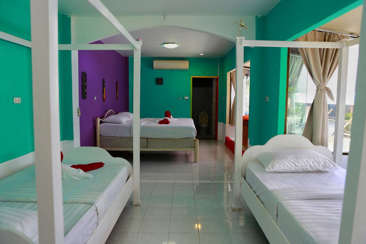 Ein Zimmer mit zwei Betten, einer violetten Wand und einer weißen Decke.