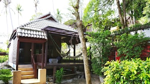 A traditional wooden house with a tiled roof, a hammock, and a small porch. - Reggae Village (Ko Pha-ngan)